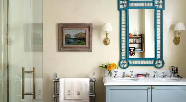 Elegante baño sin azulejos, con lavabo doble, espejo azul y cuadro de paisaje.