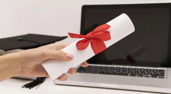 Dyplom z czerwona wstążką, czapka absolwenta i laptop. To zaproszenie dla delegacji z pracy tekst.
