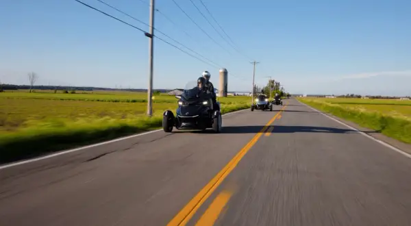 Trzykołowe motocykle jadące w kolumnie po wiejskiej drodze. Zjawisko shimmy może wystąpić przy większych prędkościach.
