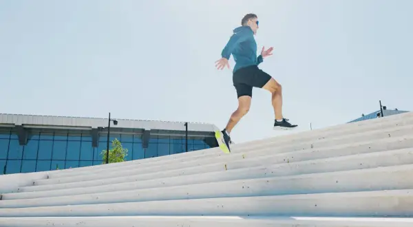 Un homme court sur des escaliers extérieurs. Est-ce que courir fait maigrir ? Oui, l'effort physique comme celui-ci aide à brûler des calories.