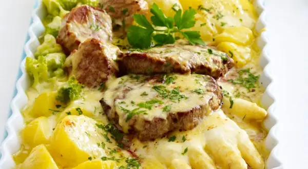 Herzhafte Spargelgerichte mit Fleisch: zarte Medaillons auf Kartoffeln und Spargel, überbacken mit Käse und garniert mit Petersilie.