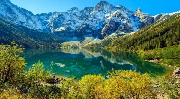 Piękne Morskie Oko, idealne na trasę. Lśniąca tafla jeziora odbija ośnieżone szczyty Tatr i jesienne lasy.