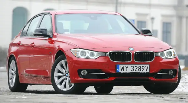 Czerwone BMW 3 F30 z polskimi tablicami rejestracyjnymi WY 3289V zaparkowane na zewnątrz.