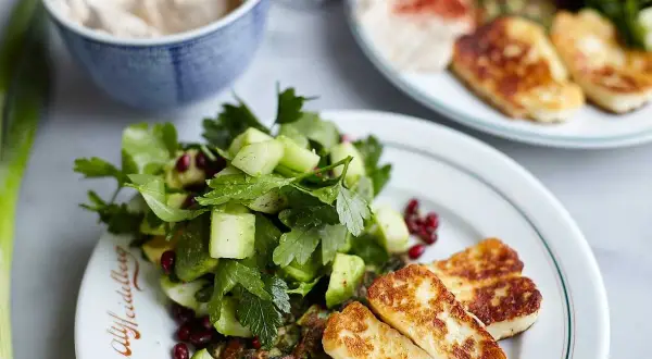 En härlig tallrik med stekt halloumi, en fräsch sallad med gurka och granatäpple, samt en grön röra. Ett perfekt halloumi recept för en lätt måltid.