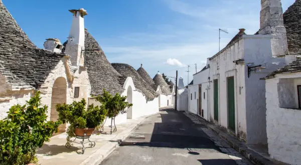 Un vicolo tra i trulli, con i loro tetti conici in pietra, mostra cosa sono i trulli, un'architettura unica della Puglia.