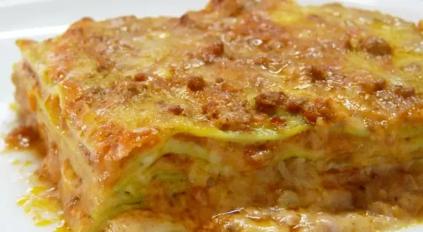 Une part de lasagne généreuse, aux couches de pâtes, sauce bolognaise et béchamel, évoquant la richesse de la lasagne origine.