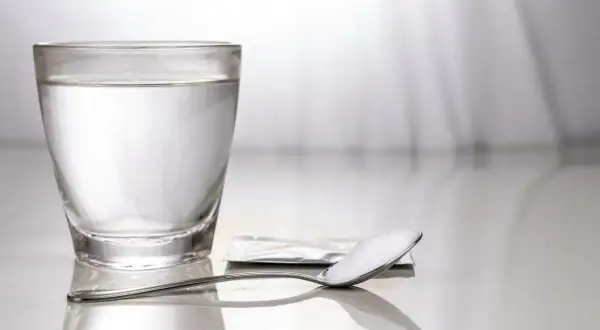 Un bicchiere d'acqua e un cucchiaino con sale, un rimedio semplice per come alzare la pressione bassa.