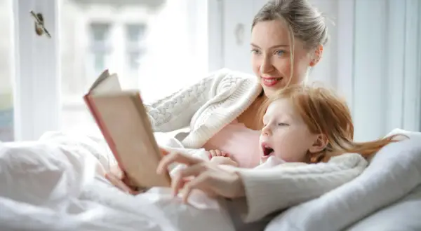 Madre e hija disfrutan de un momento acogedor con lectura en catalán para niños.
