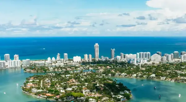 Piękna miami pogoda, błękitne niebo i turkusowa woda otaczają wyspy z luksusowymi willami i drapaczami chmur.