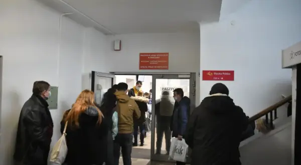 Ludzie w kolejce do punktu paszportowego w urzędzie.