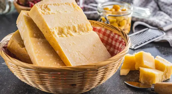 Kawałki sera Grana Padano w koszyku, obok pokrojone w kostkę. To jest właśnie to, co to jest Grana Padano.