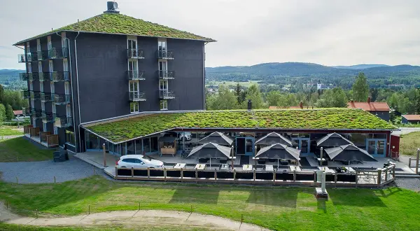 Modernt B&B Järvsö med gröna tak och utsikt över landskapet. Uteservering med parasoller.