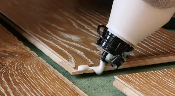 Application de colle sur du bois stratifié. Pour savoir comment enlever de la colle sur du bois stratifié, il faut agir vite.