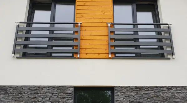 Nowoczesny portfenetr z drewnianym akcentem i ciemną balustradą. Poniżej kamienna okładzina.