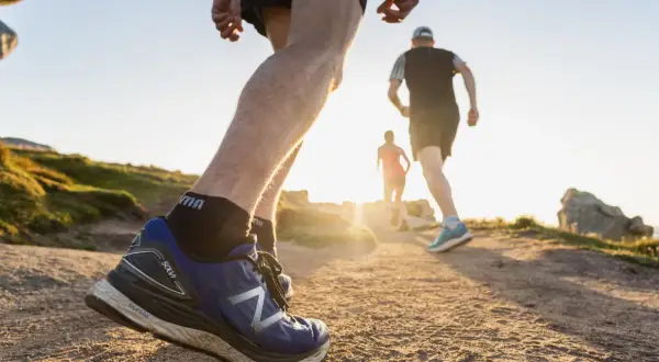 Coureurs sur un sentier de trail en Bretagne, profitant du soleil couchant sur la côte.