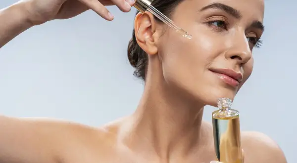 Kobieta aplikuje serum na twarz. Zastanawiasz się, jaki peeling do twarzy wybrać? Ten olejek może być odpowiedzią.