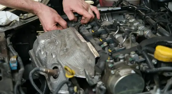Mechanik pracuje przy silniku, diagnozując objawy uszkodzonego czujnika położenia wałka rozrządu.