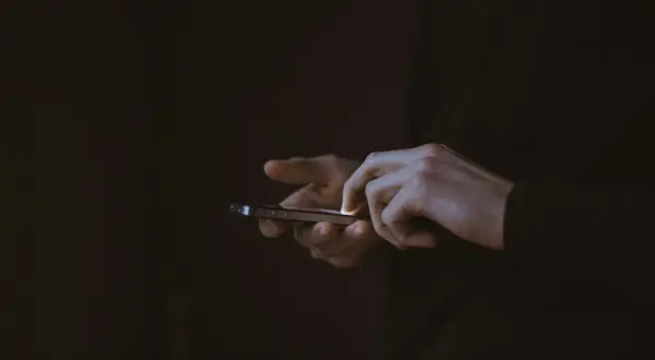 Dłonie użytkownika na ekranie smartfona, być może szukającego informacji, jak zrestartować Messengera.