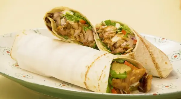 Pyszny domowy kebab w tortilli z soczystym mięsem, świeżymi warzywami i kremowym sosem. Idealny na szybki posiłek.