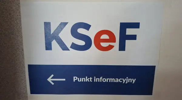 Tablica informacyjna KSeF. Strzałka w lewo wskazuje punkt informacyjny, gdzie można uzyskać pomoc podczas szkolenia.