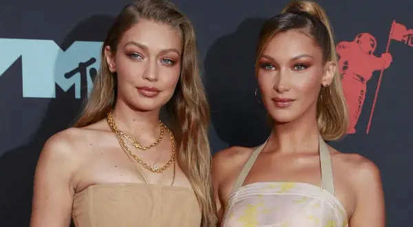 Alana Hadid y su hermana Bella posan juntas en la alfombra roja, luciendo atuendos elegantes y maquillaje impecable.