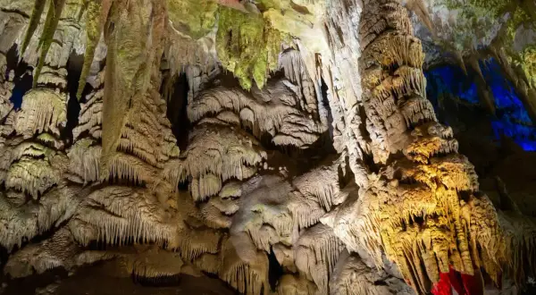 Wnętrze jaskini Prometeusza, pełne stalaktytów i stalagmitów, oświetlone ciepłym, żółtym światłem i niebieskimi akcentami.