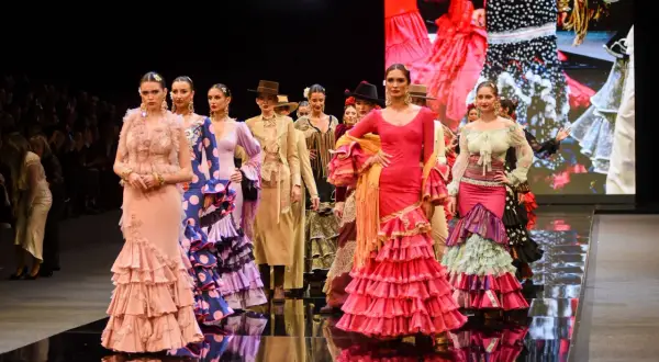 Modelos desfilan en la **pasarela SIMOF** con trajes de flamenca vibrantes y volantes.