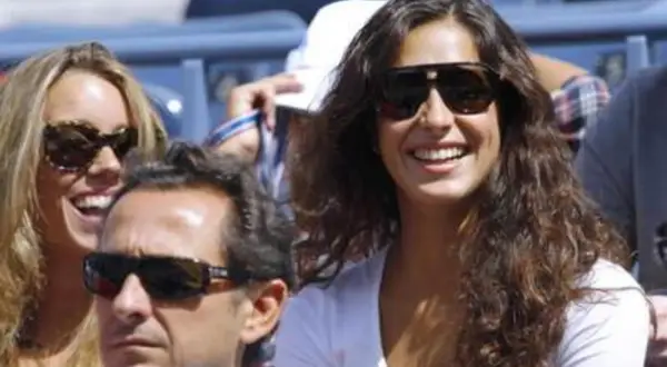 Xisca Perelló, con gafas de sol y una sonrisa radiante, disfruta de un evento deportivo junto a amigos.