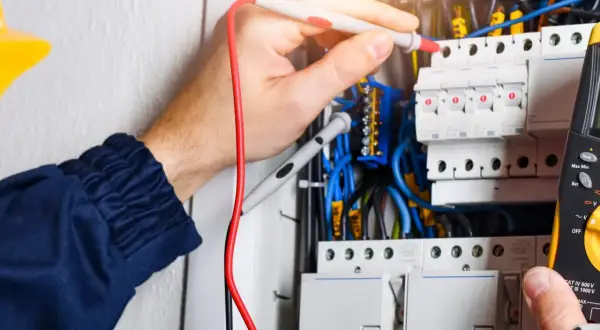Elektryk sprawdza instalację. W elektryce "L" to przewód fazowy, kluczowy dla przepływu prądu.