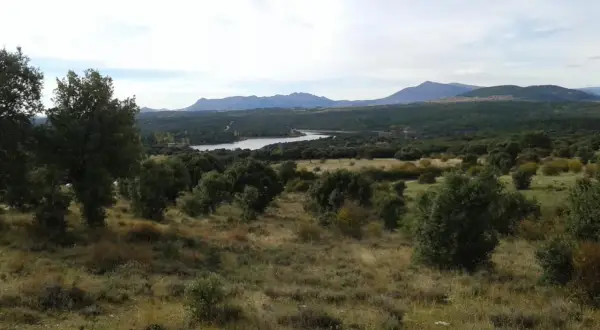 Paisaje con embalse y montañas al fondo, evocando la belleza de las paredes de Buitrago.