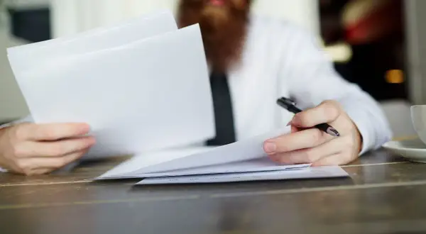 Hombre con barba revisa documentos, evaluando la validez del contrato de alquiler sin registrar.