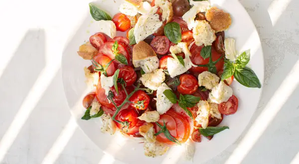 Tomate Mozzarella Salat mit geröstetem Brot und Basilikum, ein sommerlicher Genuss.