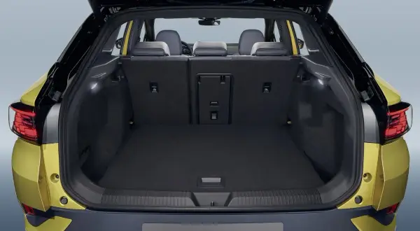 Vue du coffre ouvert d'une Volkswagen ID.4 jaune. Le volume du coffre est spacieux, prêt à accueillir vos bagages pour un long voyage.