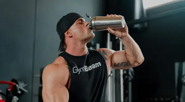 Uomo con muscoli scolpiti beve da un shaker, pronto per la sua integrazione con berberina per massimizzare i risultati.