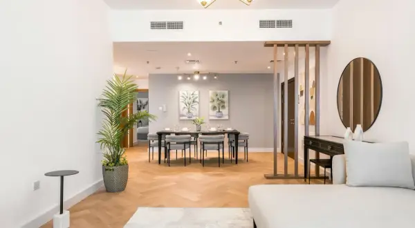 A modern living and dining area, showcasing excellent real estate photography lighting. The space features a sofa, dining table, and decorative elements.