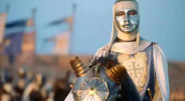 Rycerz w srebrnej masce i zbroi, z herbem Jerozolimy na płaszczu, jedzie konno. To król Baldwin IV.