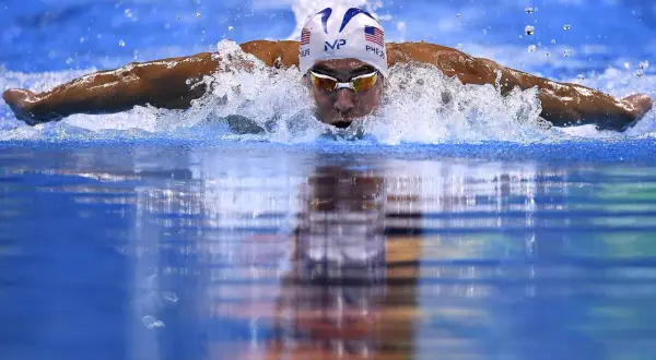 Swimmer Michael Phelps powers through the water, a blur of motion and spray. He's a master of the butterfly stroke, a style that revolutionized swimming, though who invented the butterfly stroke is debated.