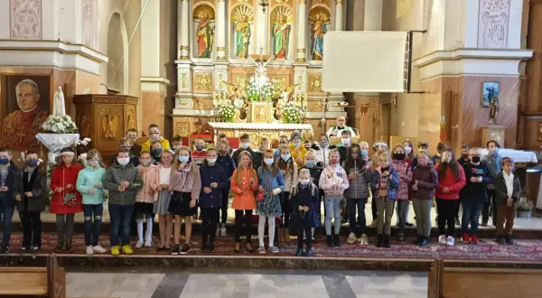 Dzieci w kościele, każde z różańcem w ręku, zastanawiają się, czy można samemu poświęcić różaniec.