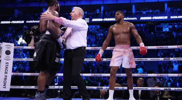 A referee separates two boxers in a ring. Interesting boxing facts: the referee's job is crucial for fighter safety.
