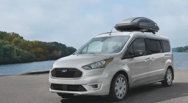 Silver Ford Transit Connect med takbox vid en sjö. Inga problem här, bara en redo för äventyr.