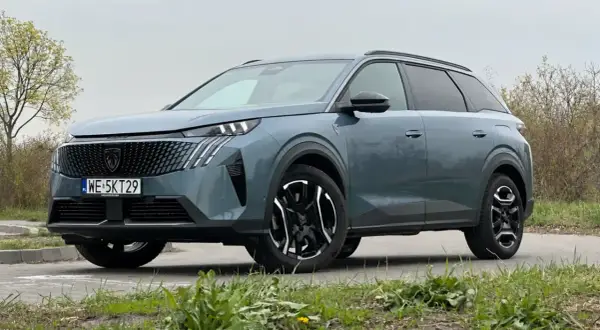 Nowy Peugeot 5008 w kolorze szarym, z czarnymi felgami i nowoczesnym grillem. Wiele osób szuka peugeot 5008 opinie przed zakupem.