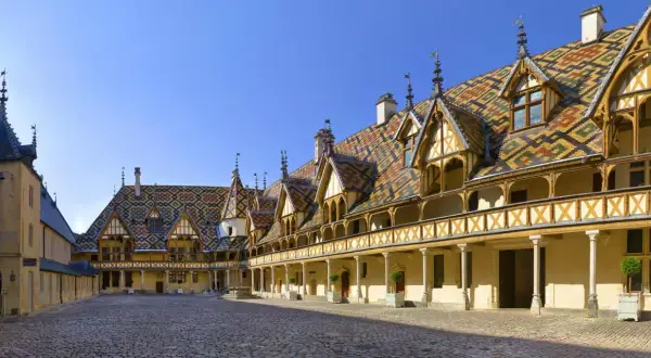 Cour intérieure des Hospices de Beaune, un joyau architectural à visiter. Toits colorés, arcades et pavés de pierre.