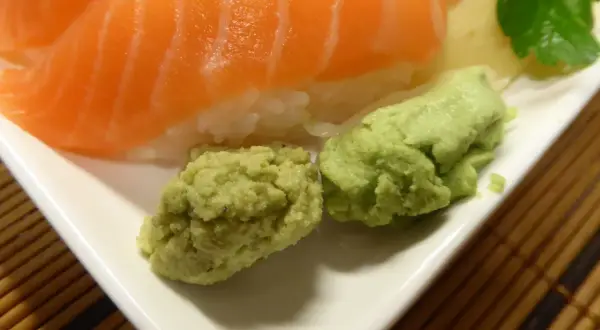 Närbild på sushi med lax och ris, serverad med två klickar grön wasabi. Perfekt för ditt wasabi recept!