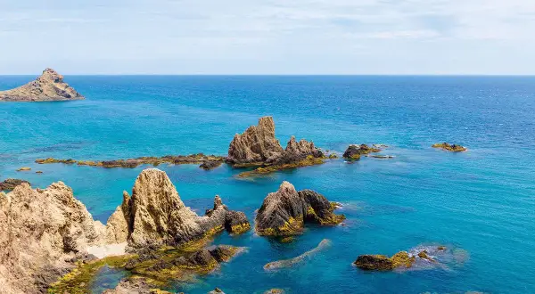 Formaciones rocosas emergen del mar turquesa, como un arrecife del dedo señalando el horizonte.