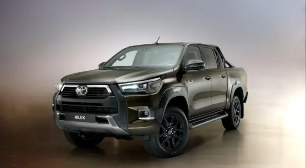 Brązowy Toyota Hilux Invincible z czarnymi felgami i relingami, gotowy na każde wyzwanie.