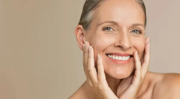 Donna sorridente con pelle matura, che mostra la sua bellezza senza età. La pelle matura da che età può essere così radiosa.