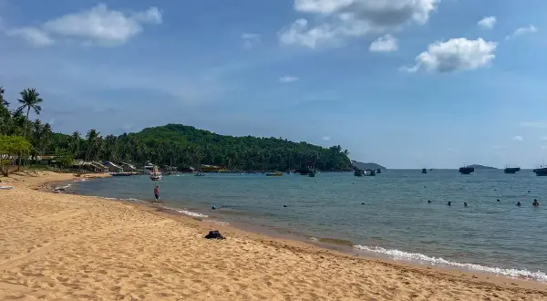 Piękna plaża z palmami, łodzie na turkusowym morzu i zielona wyspa. To idealne miejsce na odkrywanie Wietnamu na własną rękę.