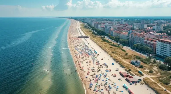 Słoneczna plaza Stogi tętni życiem. Tłumy plażowiczów, kolorowe parasole i błękitne morze tworzą wakacyjny obraz.