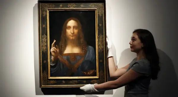 Frau mit weißen Handschuhen präsentiert das Gemälde "Salvator Mundi" von Leonardo da Vinci.