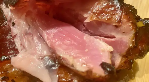 Gros plan sur des kakos de porc juteux et caramélisés, la chair rose tendre contrastant avec la peau croustillante.